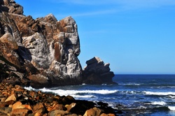Landscape view of rugged mountain side dipping into crashing surf