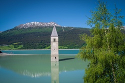Graun and a large part of Reschen village are flooded to build a dam, only the church tower is still above water.