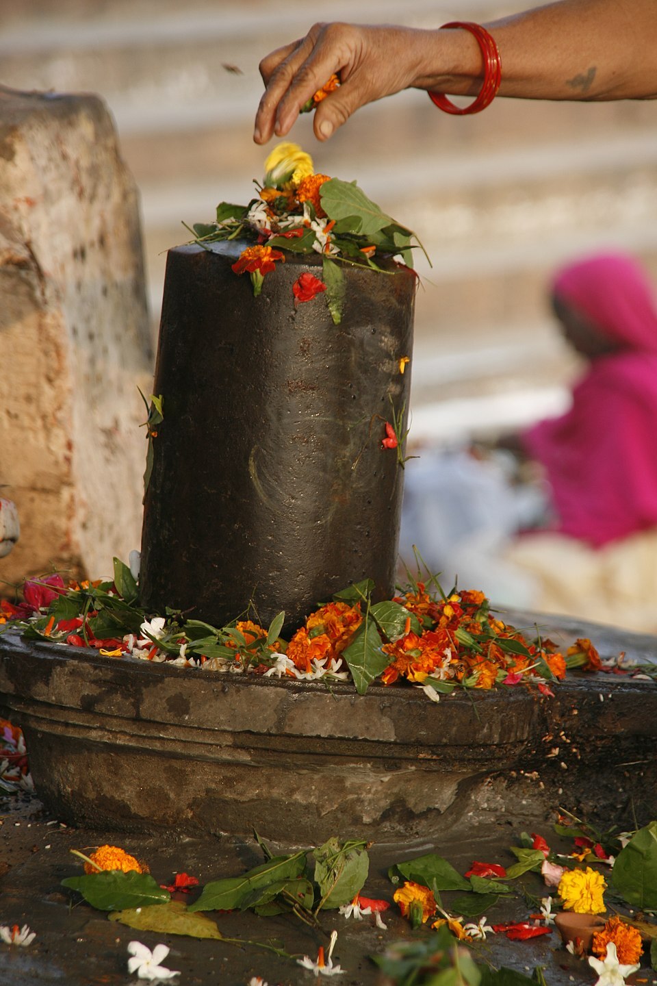 A woman spreading flowers over a lingam