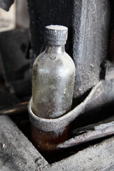 Old dusty bottle half full with oil