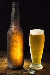 A cold bottle of beer and a cold glass of beer.